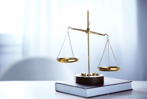 Image is of scales of justice on top of a book on a desk, concept of Cocoa Beach cyber crimes lawyer