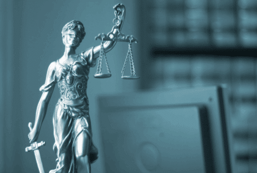 Image is of a closeup of a statuette of lady justice holding scales and sword on a lawyer's desk, concept of Melbourne criminal defense lawyers
