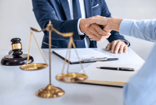 Image is of a lawyer at his desk and he is shaking hands with a client, concept of Cocoa Beach kidnapping lawyer
