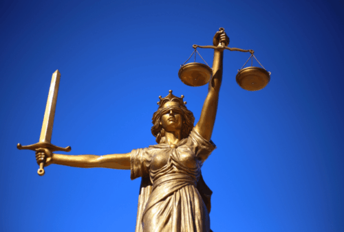 Image is of a statue of Lady Justice against a deep blue sky, concept of Melbourne law enforcement internal affairs investigation