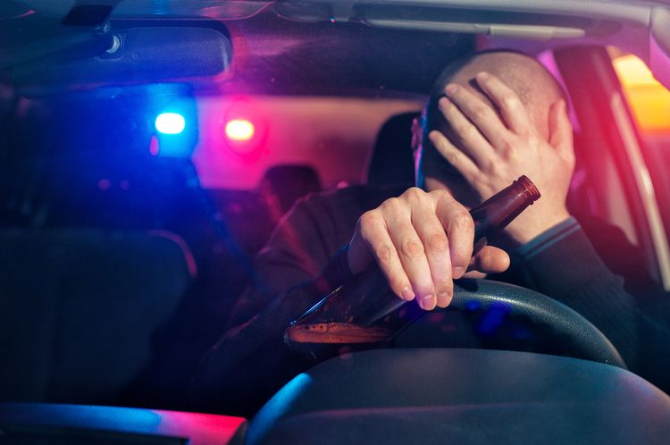 man sitting in car with beer bottle in his hand after getting pulled over by the police for a DUI arrest