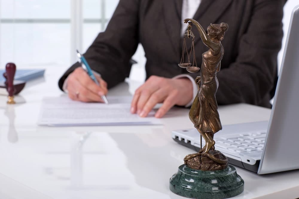 Lawyer preparing legal paperwork with Lady Justice statue.