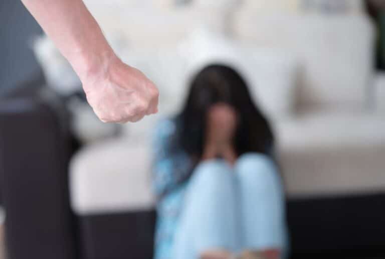 Man raising fist at woman highlighting danger of domestic violence arrest.