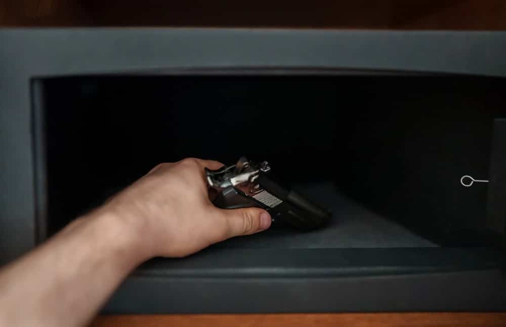 Image shows a person placing a handgun into a secure safe, concept of Florida’s laws on domestic violence and firearm access