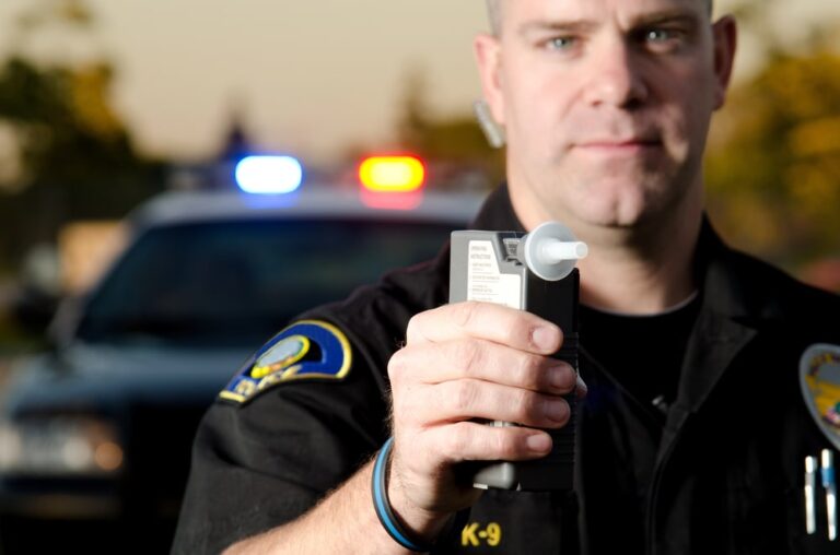 Image shows a police officer presenting a breathalyzer device, representing how DUI convictions from another state can affect a driver during a Florida traffic stop.