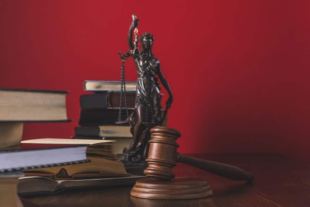 Image shows law books, a wooden gavel, and a Lady Justice statue on a desk, symbolizing the legal process involved in underage DUI cases.