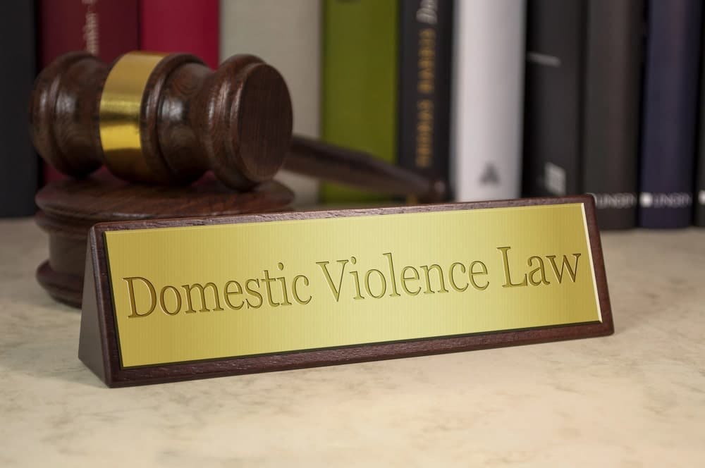 Image is of a courtroom gavel next to a domestic violence law sign, reflecting how judges evaluate safety and restrictions when issuing a domestic violence bond.