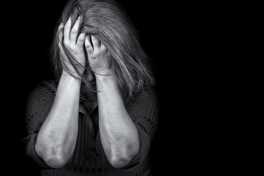 Image is of an individual holding their head in distress, representing emotional factors courts may consider when setting a domestic violence bond.