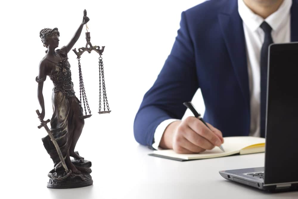 Image is of a justice statue and legal professional reviewing documents, concept of legal guidance when filing a domestic violence petition