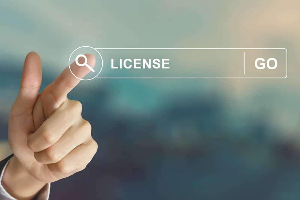 Image is of a hand pointing at an online license search bar, concept of how domestic violence charges can trigger professional license reviews and regulatory scrutiny.
