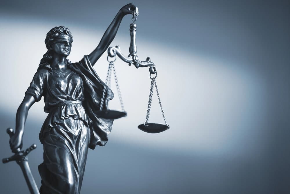 Image is of a Lady Justice statue holding scales, symbolizing legal outcomes related to the effect of a DUI on insurance decisions.
