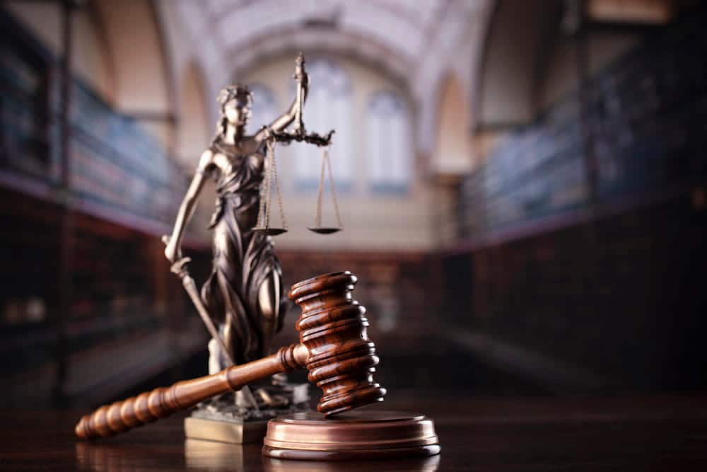 Image is of a courtroom gavel and justice statue, representing legal consequences and sentencing in Florida domestic violence repeat offender cases.