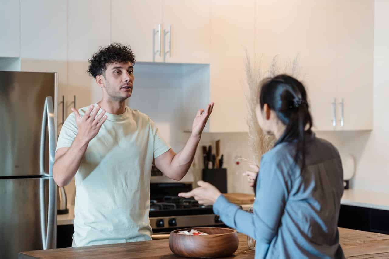 Image is of a couple arguing in a kitchen, concept of defending against allegations of verbal domestic violence without physical injury.