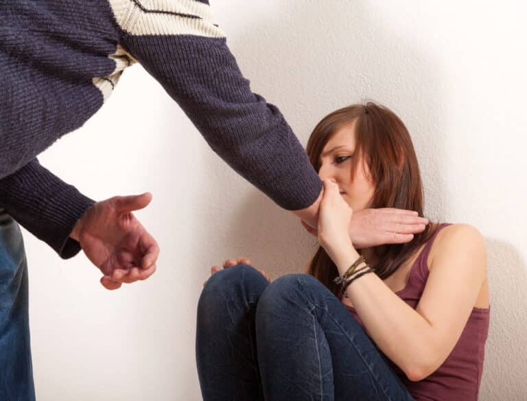 Image shows a woman shielding herself from an approaching hand, representing victim fear and behavioral evidence of domestic violence in Cocoa Beach
