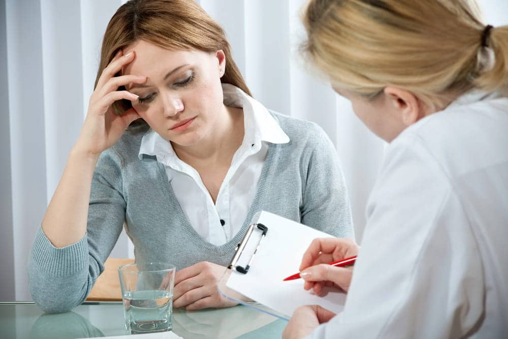 Image is of a woman speaking with a therapist who is taking notes during a counseling session, concept of domestic violence and mental health assessment and guidance.