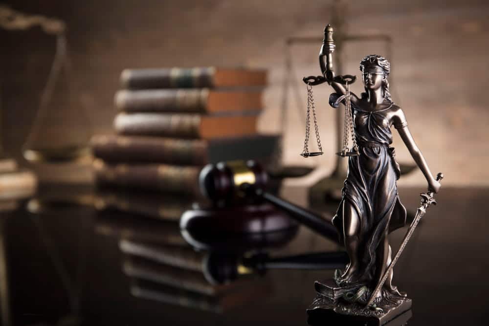 Image is of a Lady Justice statue with scales and gavel on a desk, concept of DUI arraignment process and courtroom justice