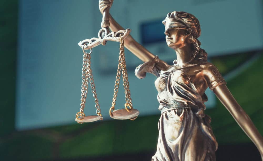 Image is of a close up of scales of justice held by Lady Justice statue, concept of DUI arraignment and legal balance in court