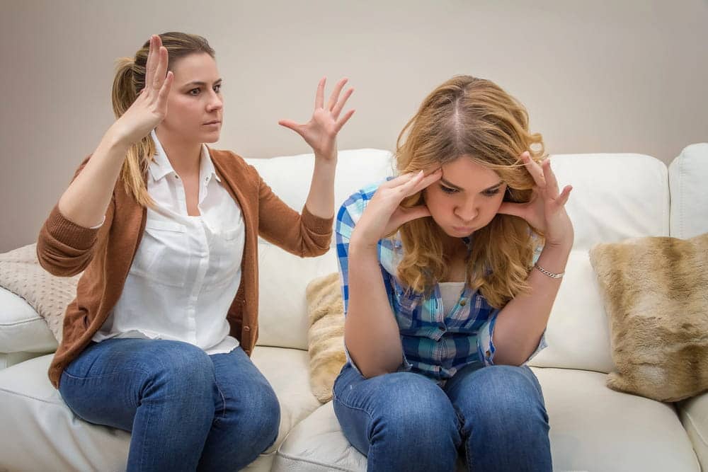 Image is of two women in a tense argument on a couch, concept of domestic violence in same sex relationships