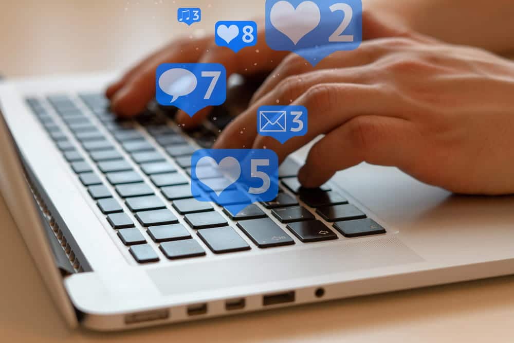 Image is of hands typing on a laptop with social media notifications appearing, concept of digital evidence in DV cases in Cocoa Beach