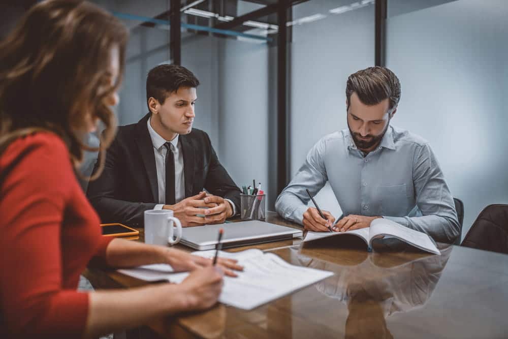 Image is of a couple reviewing and signing legal paperwork with professionals, concept of DV cases in Cocoa Beach and mediation agreement discussions.