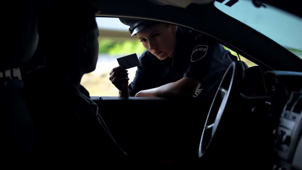 Image is of a police officer speaking with a driver during a roadside traffic stop, concept of DUI penalties and law enforcement investigation in Cocoa Beach.