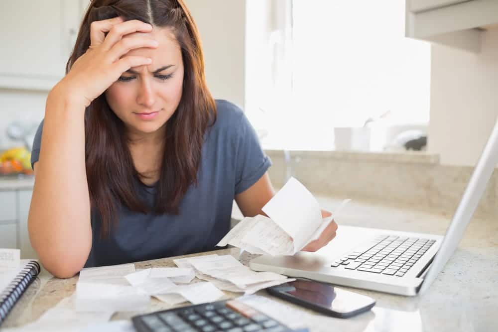 Image is of a woman reviewing receipts and financial records at home, concept of domestic violence in Cocoa Beach and financial abuse affecting personal finances.