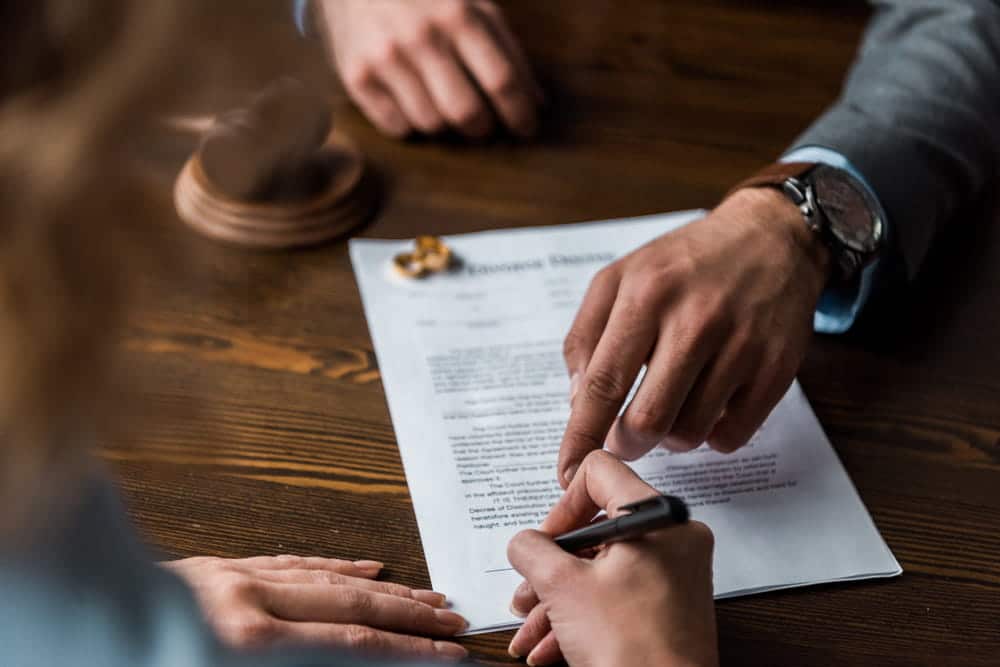 Image is of a person signing divorce documents with an attorney, concept of domestic violence affecting divorce in Cocoa Beach.