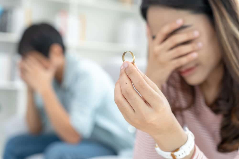 Image is of a distressed spouse holding a wedding ring, concept of the emotional effects of domestic violence during divorce in Cocoa Beach.