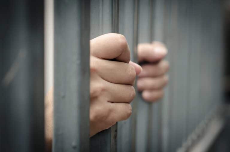 Image is of hands holding jail bars, concept of a Cocoa Beach DUI case involving possible jail time.