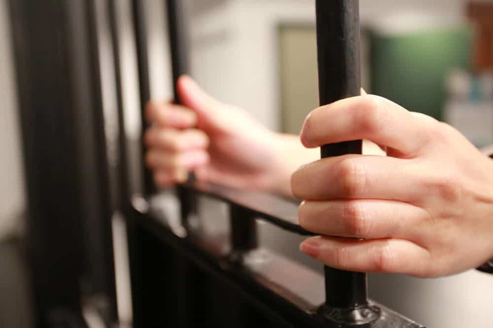 Image is of a person gripping jail bars, concept of Cocoa Beach DUI penalties and possible incarceration.