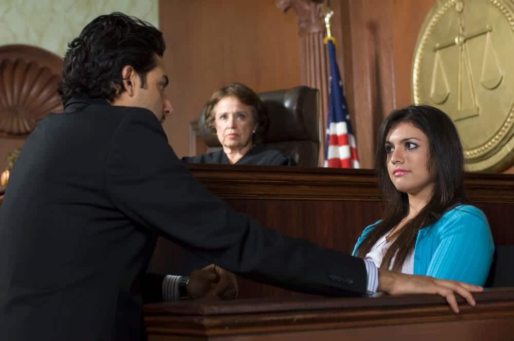 Image is of a victim speaking with an attorney in a courtroom, concept of victim participation after domestic violence in Cocoa Beach.