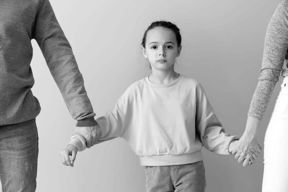 Image is of a child standing between two parents during a custody dispute, concept of child custody in Cocoa Beach and DUI-related family law issues.