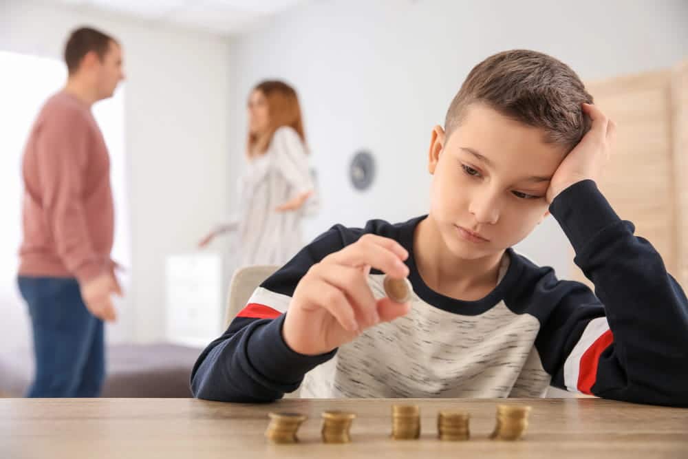 Image is of a worried child sitting while parents argue in the background, concept of restricting visitation after DV in Cocoa Beach