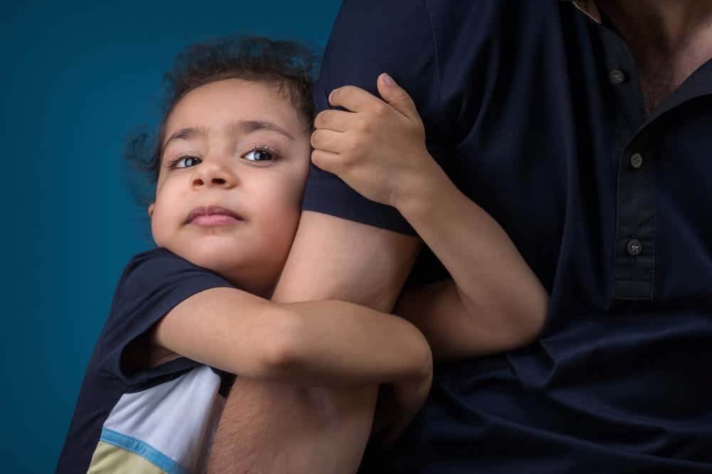 Image is of a young child holding tightly to a parent for comfort, concept of restricting visitation after DV in Cocoa Beach