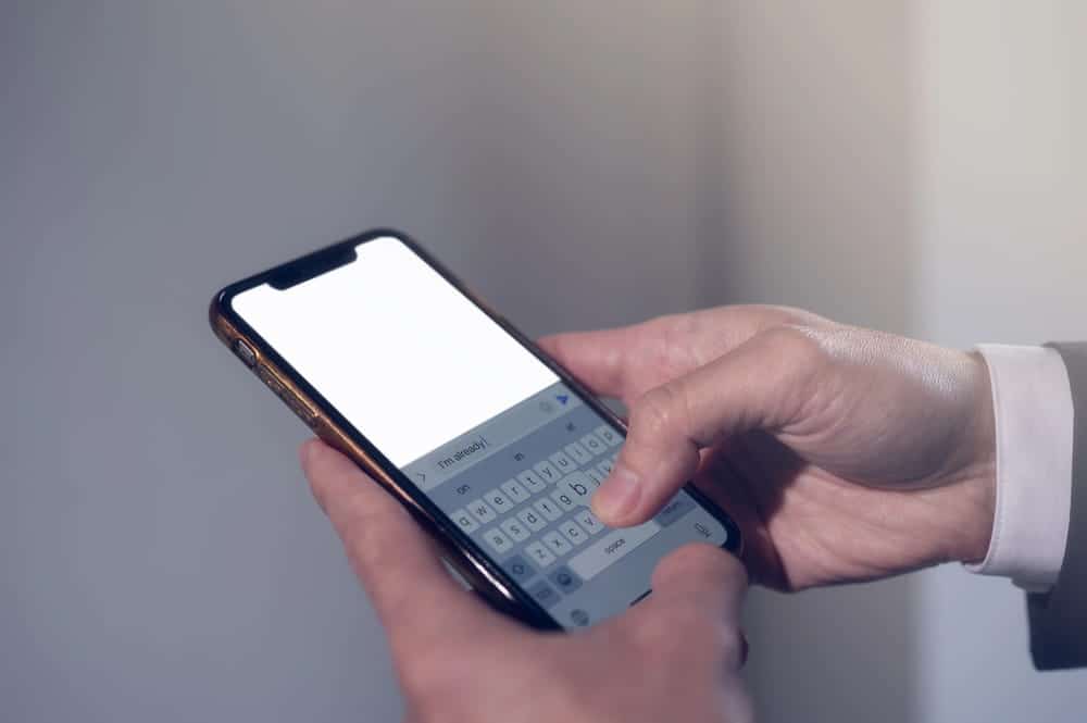 Image is of a person typing a message on a smartphone, concept of DV defense mistakes involving digital communications.