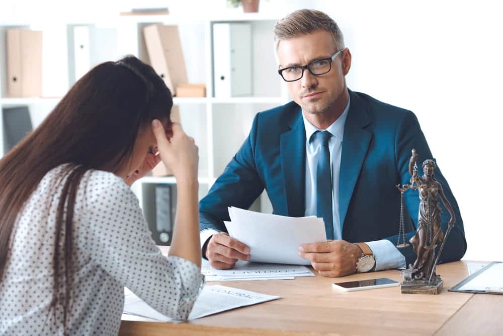 Image is of a lawyer reviewing documents with a client, concept of DV defense mistakes during a pending case.