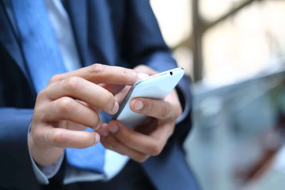 Image is of a person reviewing information on a smartphone, concept of DV defense mistakes involving phone communications.