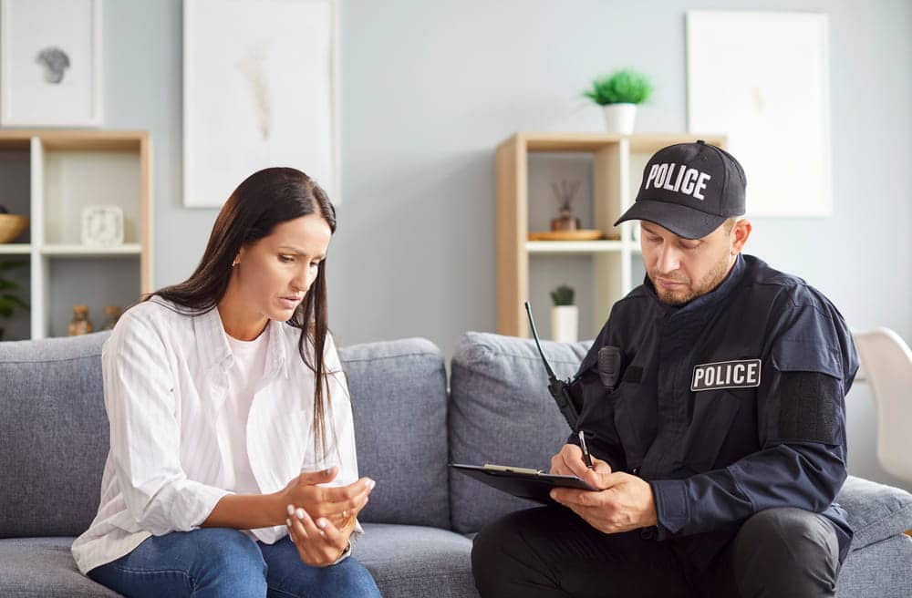 Image is of a police officer taking a statement from a woman, concept of DV defense mistakes during an investigation.