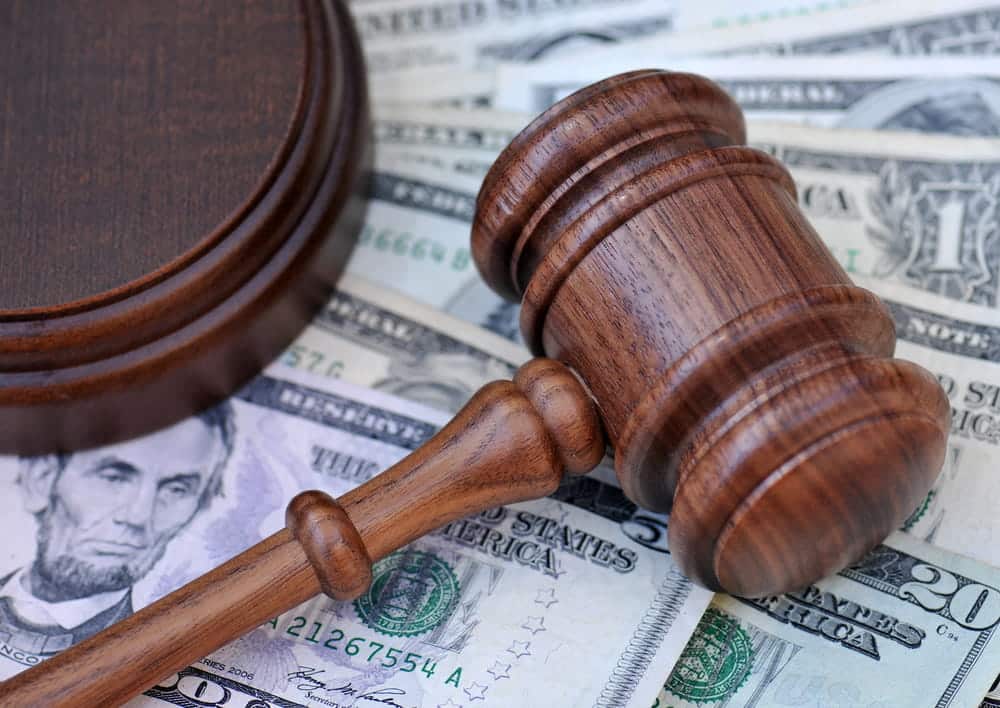 Image is of a judge’s gavel resting on money, concept of bond conditions at a DUI bond hearing.
