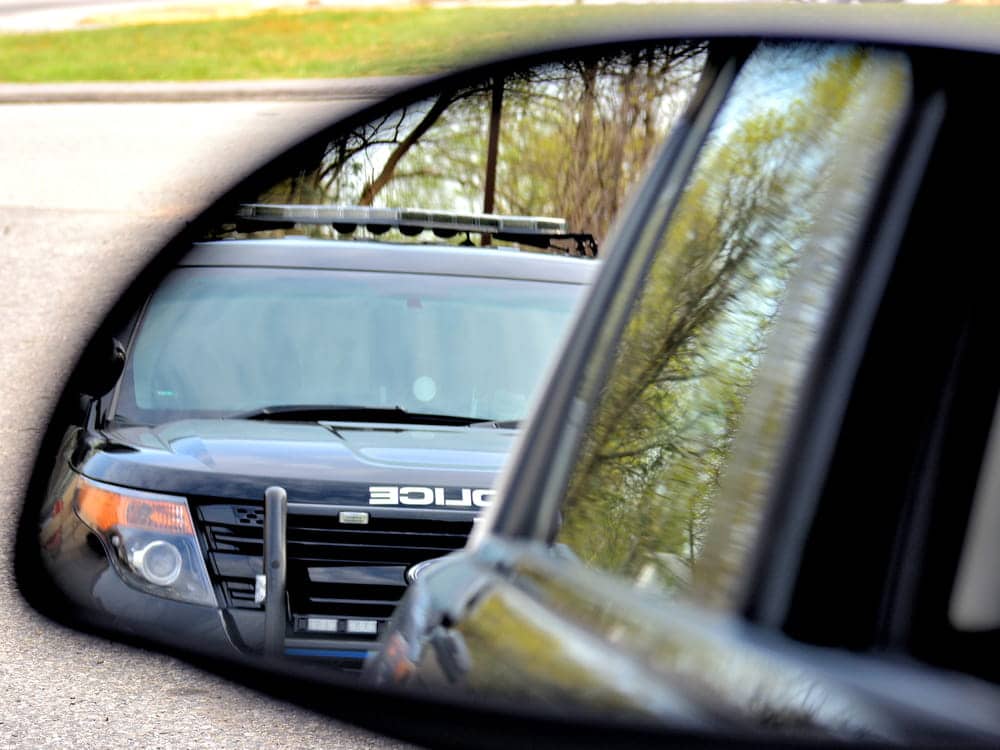 Image of a police vehicle reflected in a car's side mirror, illustrating traffic enforcement targeting Brevard County super speeders.