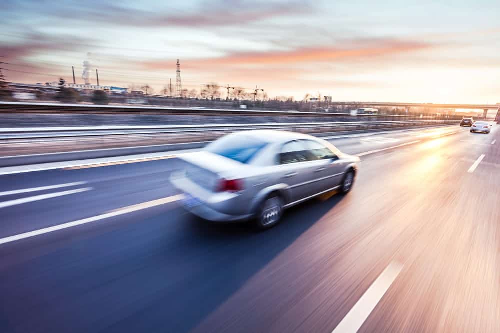 Image of a silver car traveling along a highway at sunset, illustrating high-speed driving concerns involving Brevard County super speeders.