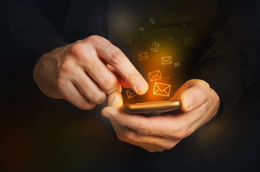 Image is of a person using a smartphone with glowing digital message icons, concept of text message evidence in a Cocoa Beach DV case.