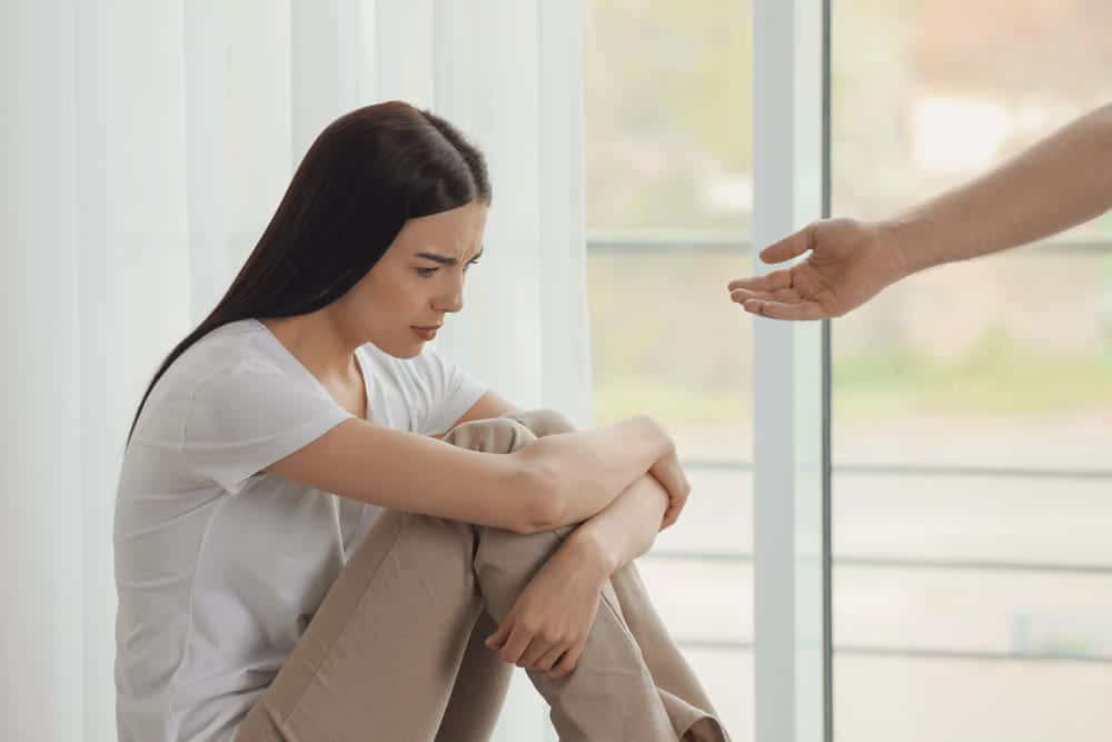 Image shows a distressed woman sitting alone while another person offers support, illustrating the emotional circumstances a DV accuser may face when considering recanting allegations in Cocoa Beach.